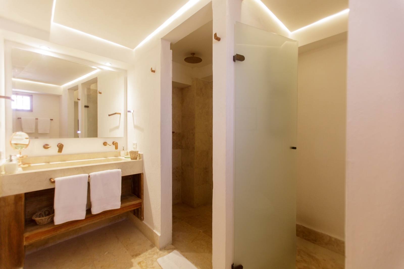 Casa Palmas luxury en-suite bathroom with double marble sink, bronze gold fixtures, and backlit ceiling