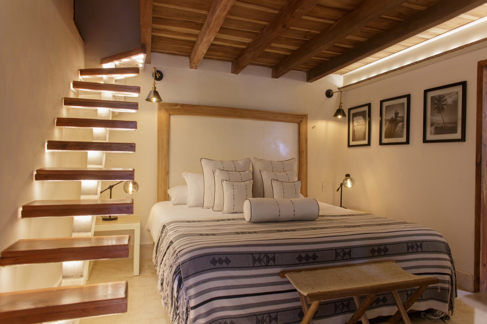 Casa Palmas Duplex Standard bedroom with illuminated floating wood staircase, king bed, artisan linens, and colonial beam ceiling