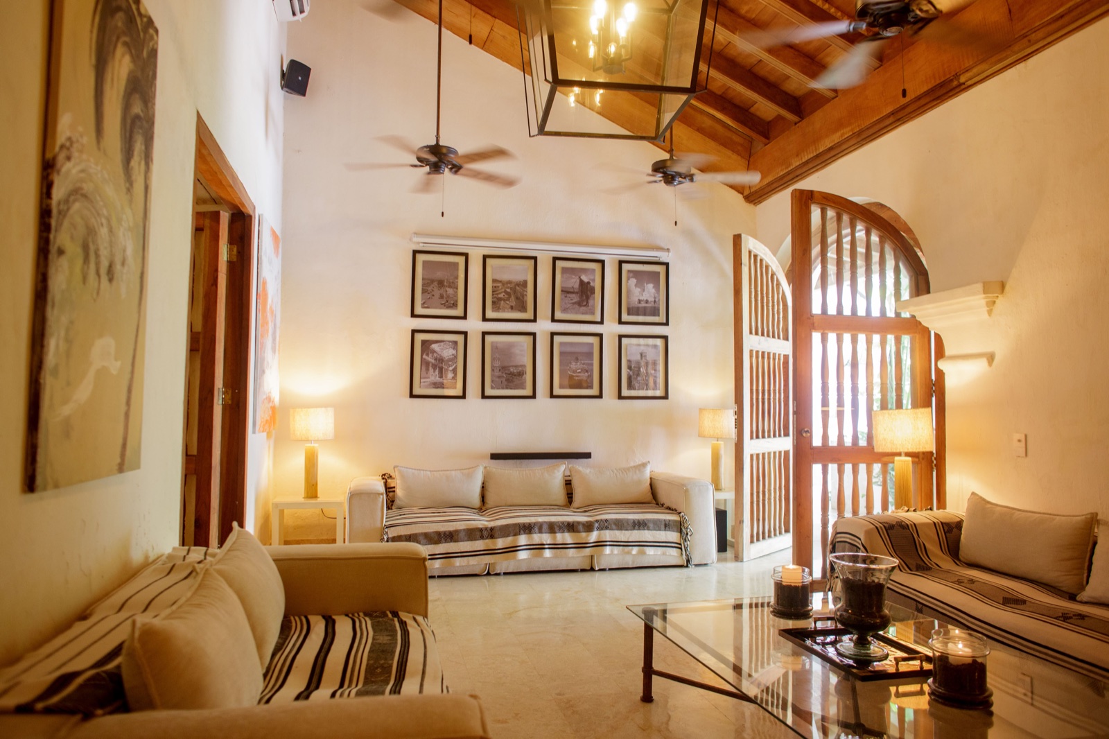 Casa Palmas grand living room with soaring colonial wood-beam ceiling, Moorish arched doorway, striped linen sofas, and original artwork