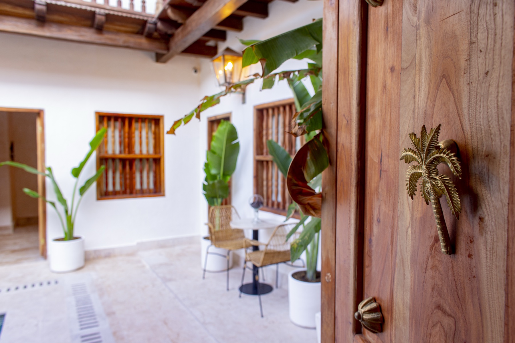 Casa Palmas colonial entrance door with handcrafted brass palm tree handle opening to the tropical courtyard