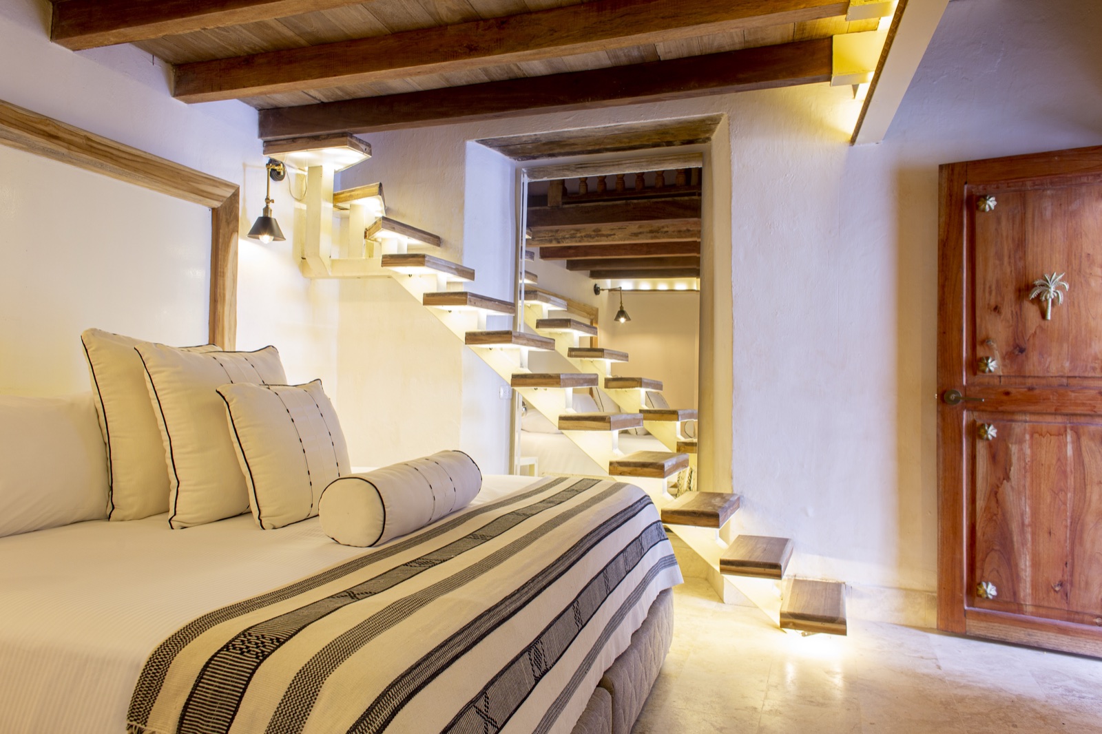 Casa Palmas duplex suite architectural floating staircase with under-step LED lighting and colonial teak door detail
